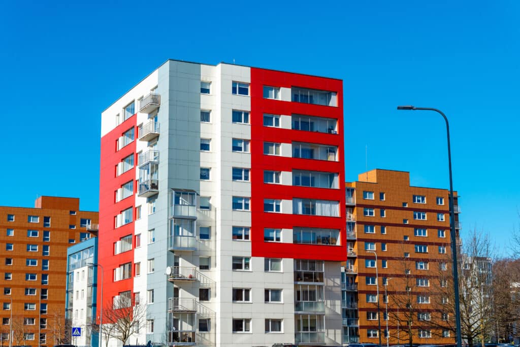 A newly built building in nice bright colors with apartments for sale. Red orange and green block of flats. Newly finished modern style apartment building in freshly renovated residential area. Multifamily owners and operators concept.