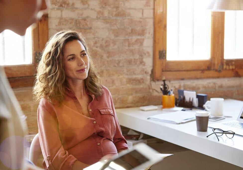 pregnant property manager sitting at her desk looking away