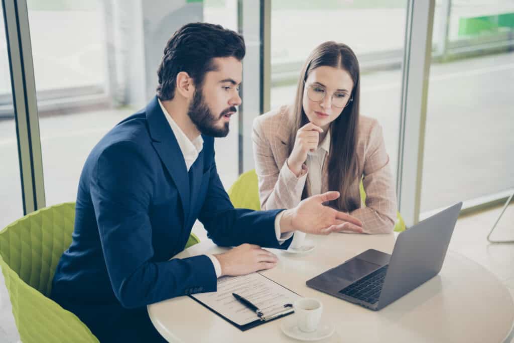 property manager and director of marketing sitting at desk looking at laptop, reviewing kingsleysurvey results from resident survey