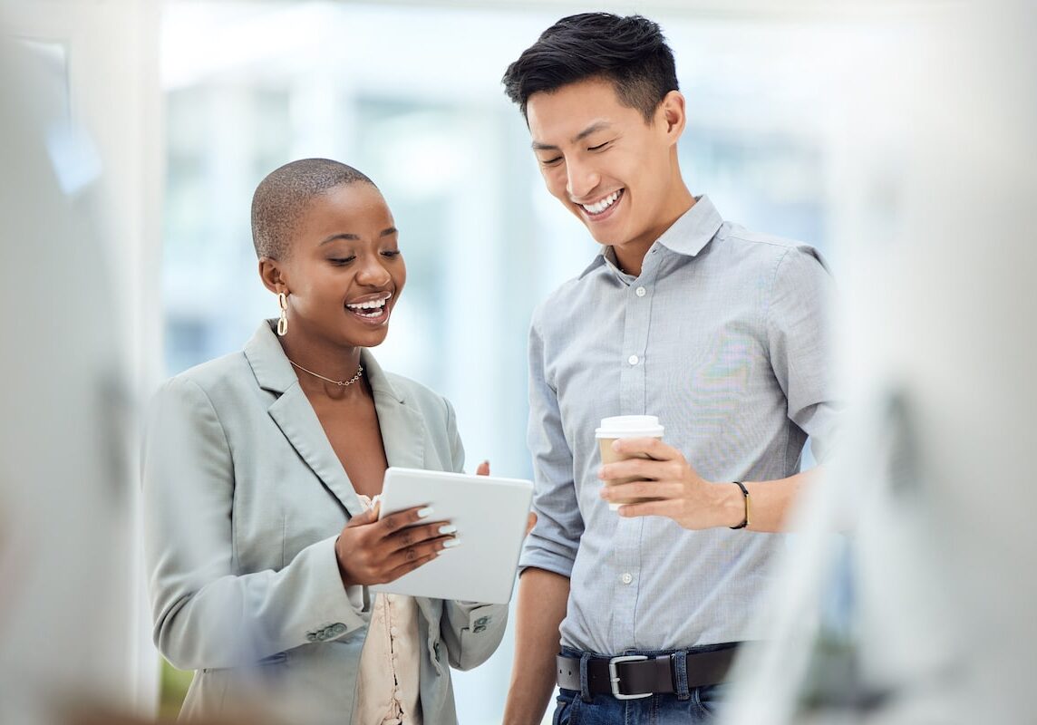 employees smiling at tablet, looking at employee satisfaction survey